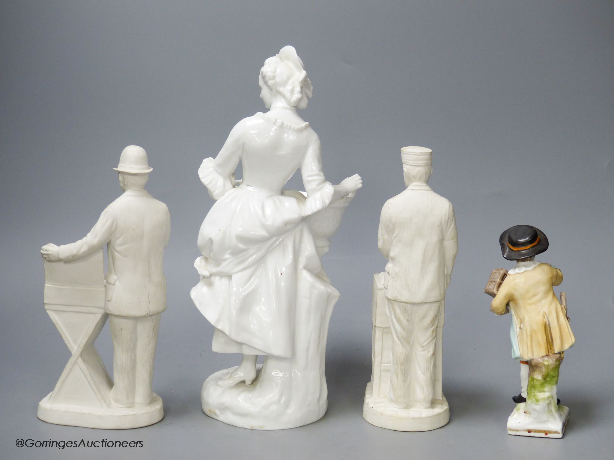 A French white glazed figure, a pair of biscuit porcelain figures of street sellers and a Berlin figure, tallest 27cm